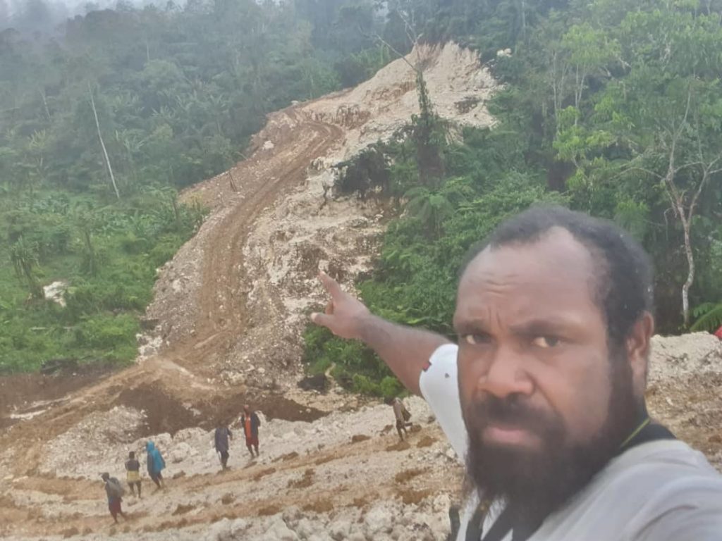 PNG coffee farmer points to road 